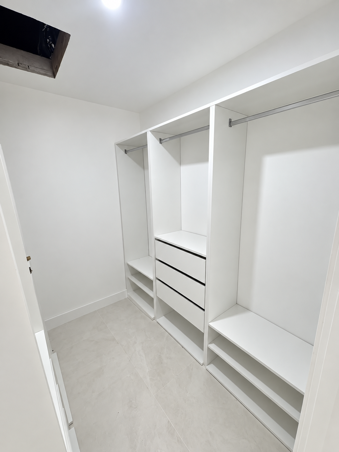 White custom walk-in closet with drawers, shelving, and hanging storage
